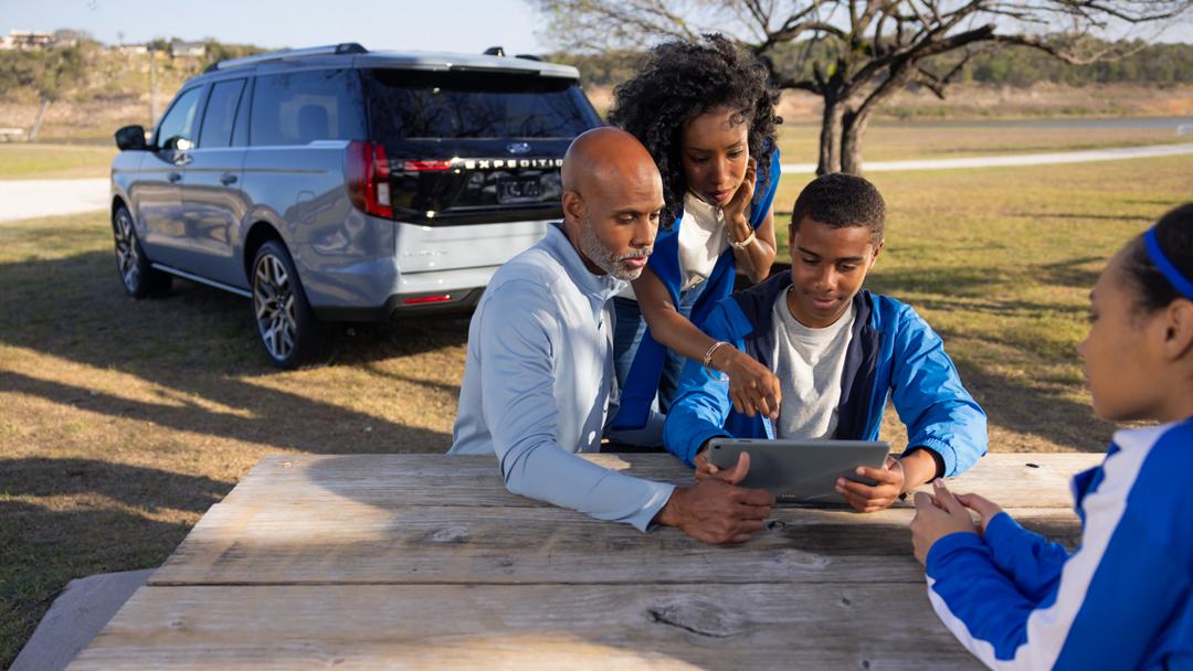 Family enjoying time together beside a Ford Expedition